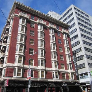 Exterior of the Mosser Hotel, with vertical sign and vibrant red brick hue.