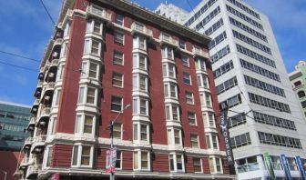 Exterior of the Mosser Hotel, with vertical sign and vibrant red brick hue.