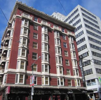 Exterior of the Mosser Hotel, with vertical sign and vibrant red brick hue.