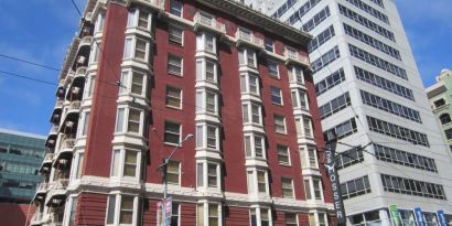 Exterior of the Mosser Hotel, with vertical sign and vibrant red brick hue.