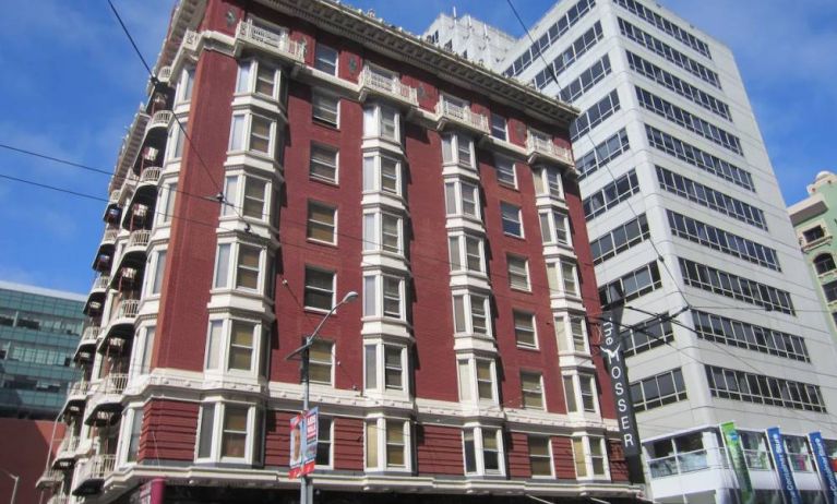 Exterior of the Mosser Hotel, with vertical sign and vibrant red brick hue.