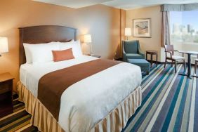 Double bed guest room in Best Western Plus Winnipeg Airport, featuring window, armchair, and foot stool.