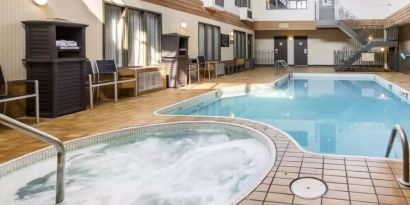 The hotel’s indoor swimming pool has chairs and towels nearby, and an adjacent hot tub.