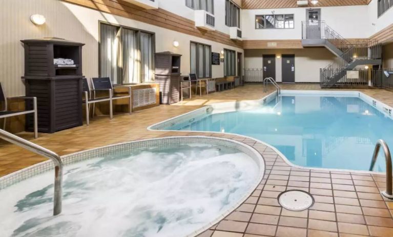 The hotel’s indoor swimming pool has chairs and towels nearby, and an adjacent hot tub.