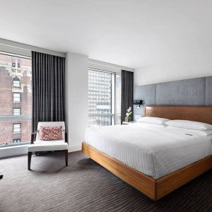 A guest room of the Hotel 48LEX New York, with large double bed, and workspace desk and chair.