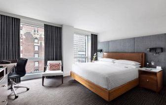 A guest room of the Hotel 48LEX New York, with large double bed, and workspace desk and chair.