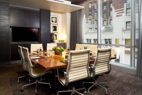 One of the hotel’s meeting rooms, with eight chairs around a long table, and a large TV screen.