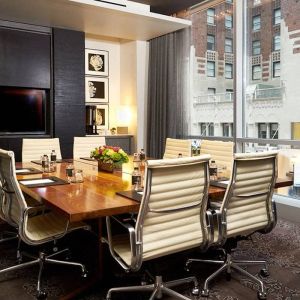 One of the hotel’s meeting rooms, with eight chairs around a long table, and a large TV screen.