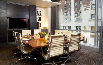 One of the hotel’s meeting rooms, with eight chairs around a long table, and a large TV screen.