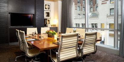 One of the hotel’s meeting rooms, with eight chairs around a long table, and a large TV screen.