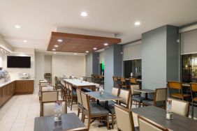 The hotel’s breakfast area, with assorted table sizes, chairs, and hard floor.