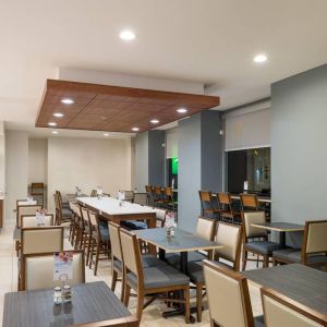 The hotel’s breakfast area, with assorted table sizes, chairs, and hard floor.