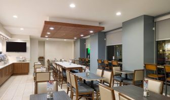 The hotel’s breakfast area, with assorted table sizes, chairs, and hard floor.