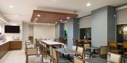 The hotel’s breakfast area, with assorted table sizes, chairs, and hard floor.