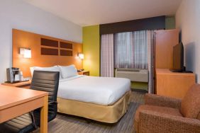 One of Holiday Inn Express Times Square’s guest rooms, with comfy chair, space for working, and window, plus double bed.