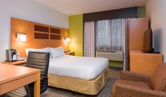 One of Holiday Inn Express Times Square’s guest rooms, with comfy chair, space for working, and window, plus double bed.