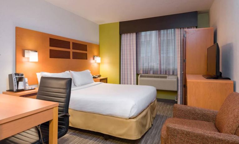 One of Holiday Inn Express Times Square’s guest rooms, with comfy chair, space for working, and window, plus double bed.