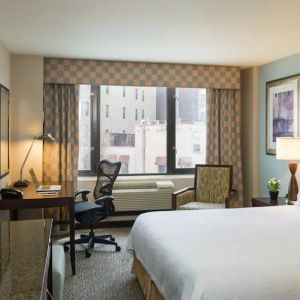 Guest room in the Hilton Garden Inn Tribeca, furnished with large bed, desk and chair for working, and TV.