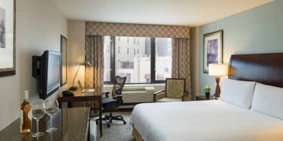 Guest room in the Hilton Garden Inn Tribeca, furnished with large bed, desk and chair for working, and TV.