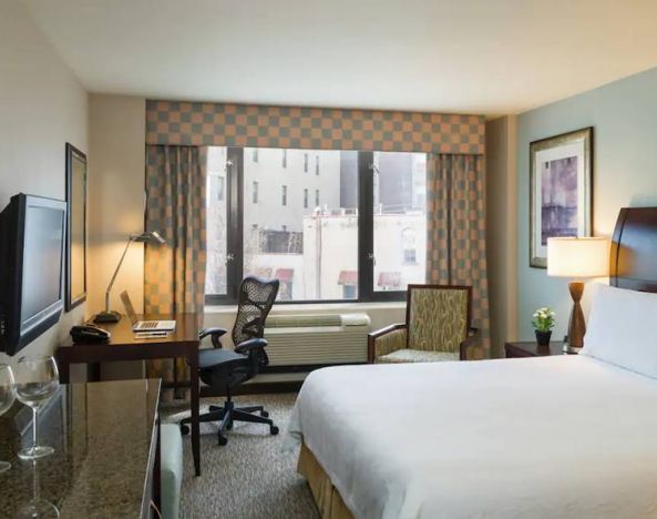 Guest room in the Hilton Garden Inn Tribeca, furnished with large bed, desk and chair for working, and TV.