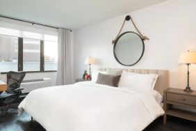 The Hilton Garden Inn Tribeca’s penthouse suite guest room, with large bed, window, and workspace.