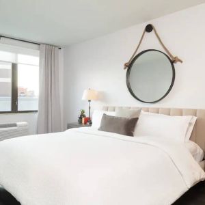 The Hilton Garden Inn Tribeca’s penthouse suite guest room, with large bed, window, and workspace.