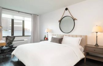 The Hilton Garden Inn Tribeca’s penthouse suite guest room, with large bed, window, and workspace.