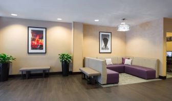 Hampton Inn Times Square South’s lobby lounge, with art on the walls and comfortable sofa seating.