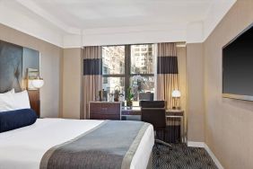 Guest room in the New Yorker Hotel, A Wyndham Hotel, with double bed and workspace desk and chair.