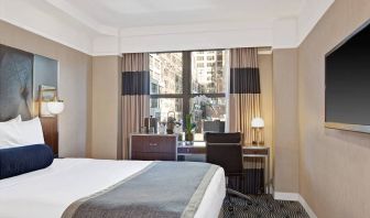 Guest room in the New Yorker Hotel, A Wyndham Hotel, with double bed and workspace desk and chair.