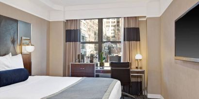 Guest room in the New Yorker Hotel, A Wyndham Hotel, with double bed and workspace desk and chair.