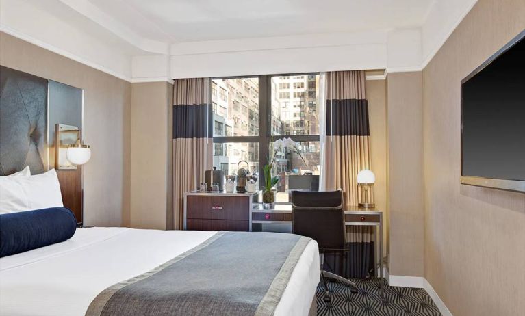 Guest room in the New Yorker Hotel, A Wyndham Hotel, with double bed and workspace desk and chair.