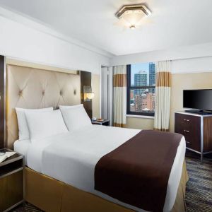 A guest room in the New Yorker Hotel, A Wyndham Hotel with double bed and window.