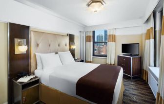 A guest room in the New Yorker Hotel, A Wyndham Hotel with double bed and window.