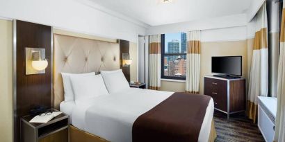 A guest room in the New Yorker Hotel, A Wyndham Hotel with double bed and window.