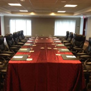 Meeting room with a dozen leather chairs arranged around a long table.