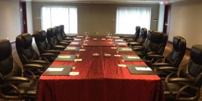 Meeting room with a dozen leather chairs arranged around a long table.