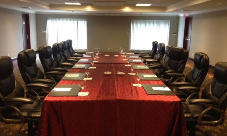 Meeting room with a dozen leather chairs arranged around a long table.