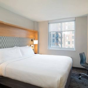 One of Holiday Inn Express Wall Street’s guest rooms, complete with double bed, window, and workspace chair and desk.