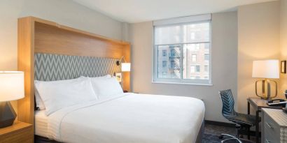 One of Holiday Inn Express Wall Street’s guest rooms, complete with double bed, window, and workspace chair and desk.