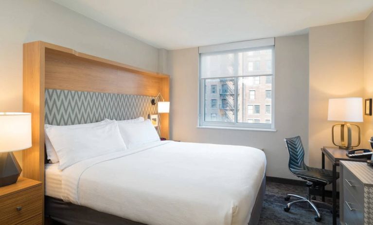 One of Holiday Inn Express Wall Street’s guest rooms, complete with double bed, window, and workspace chair and desk.