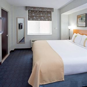 Double bed guest room in the Holiday Inn Express Wall Street, with window, TV, and mirror.