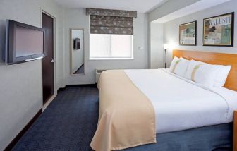 Double bed guest room in the Holiday Inn Express Wall Street, with window, TV, and mirror.