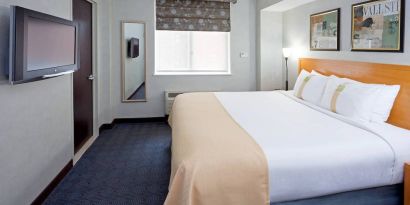 Double bed guest room in the Holiday Inn Express Wall Street, with window, TV, and mirror.