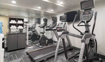 Various exercise machines, towels, and TV in the hotel’s fitness center.