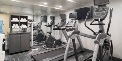 Various exercise machines, towels, and TV in the hotel’s fitness center.