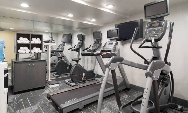 Various exercise machines, towels, and TV in the hotel’s fitness center.