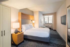 Guest room in the Holiday Inn Express Wall Street, with large television, chairs, and window.