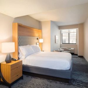 Guest room in the Holiday Inn Express Wall Street, with large television, chairs, and window.