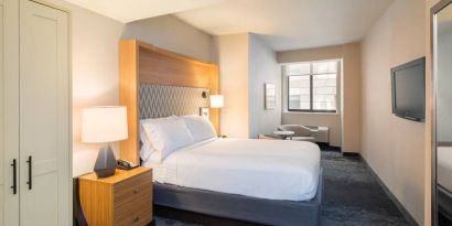 Guest room in the Holiday Inn Express Wall Street, with large television, chairs, and window.